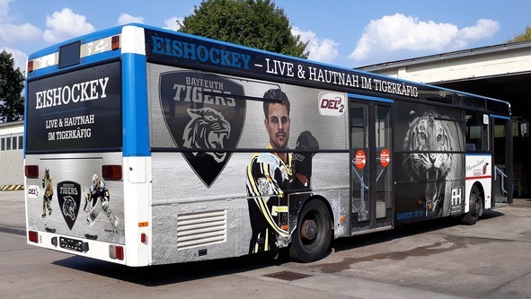 Ein Bus, der mit Hilfe von bedruckten Folien, mit der Werbung für eine Eishockeymannschaft beklebt wurde.