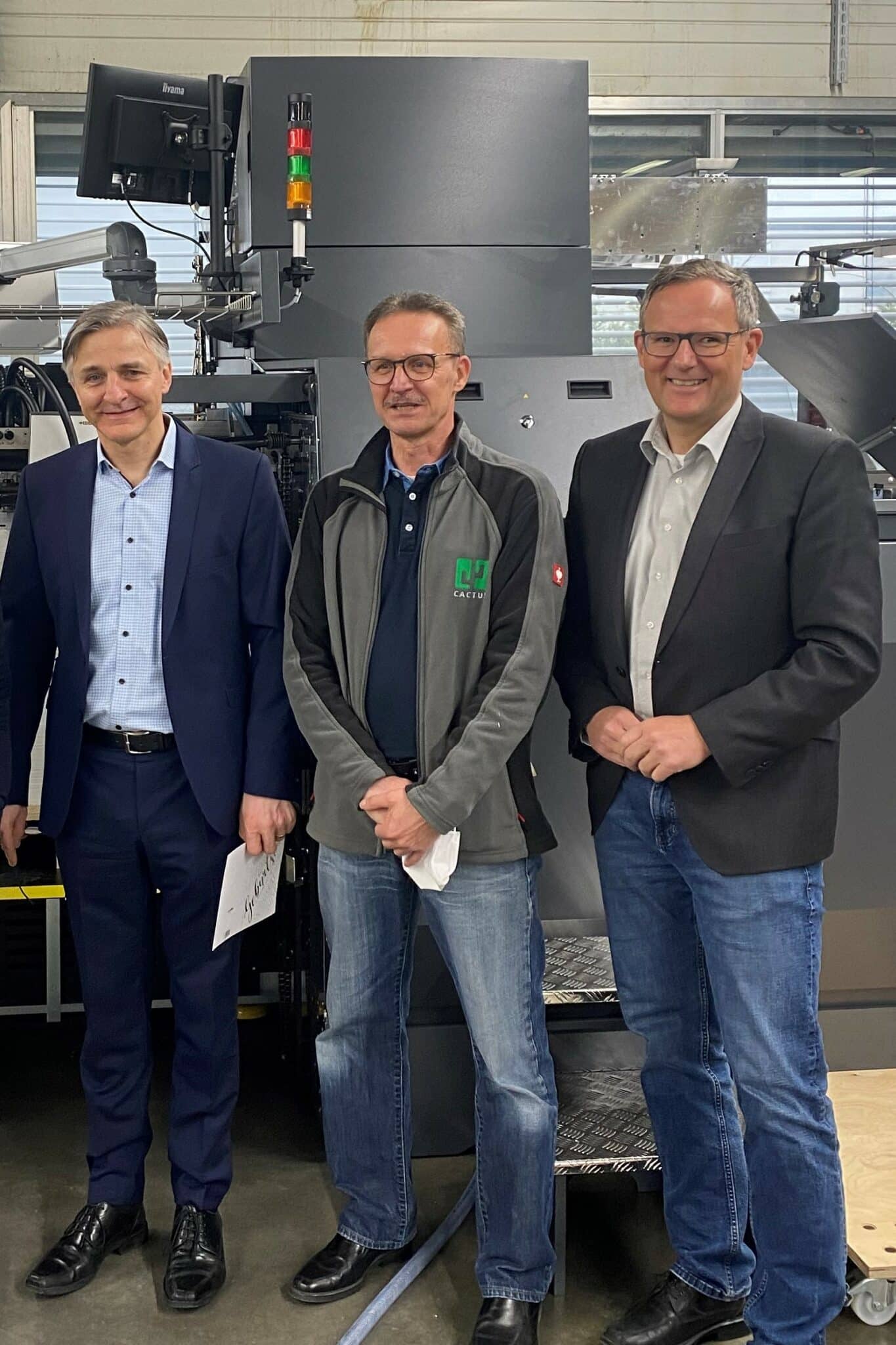 Davor Vnucec, Produktionsleiter Cactus (Mitte), Bernd Sauter, KAMA Geschäftsführer (links) und Frank Riedmüller von der MMV Leasing vor der installierten Stanz- und Veredelungsmaschine.